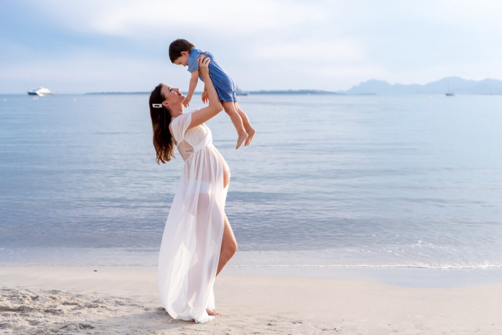 Mama embarazada disfrutando con su hijo en la playa de Valencia