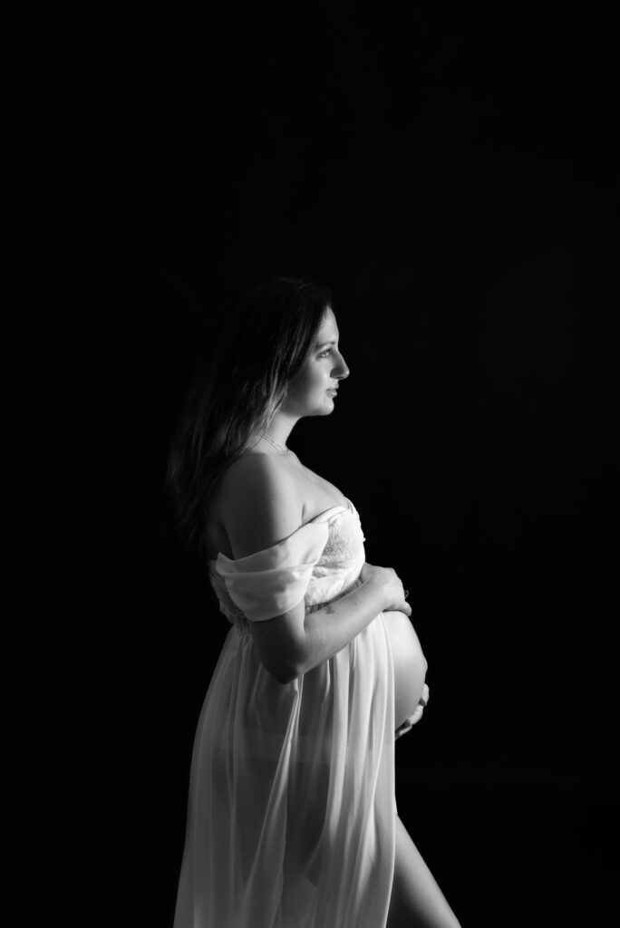 Retrato artístico de futura mamá en estudio con fondo negro