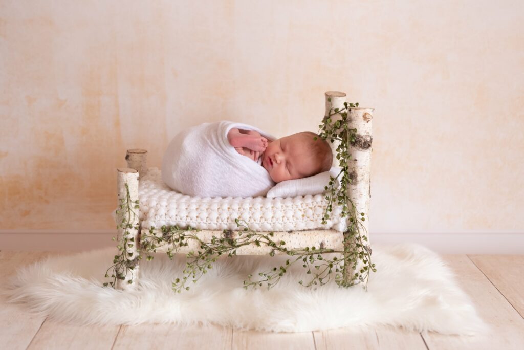 Fotografía de bebé en cama con hojas Valencia