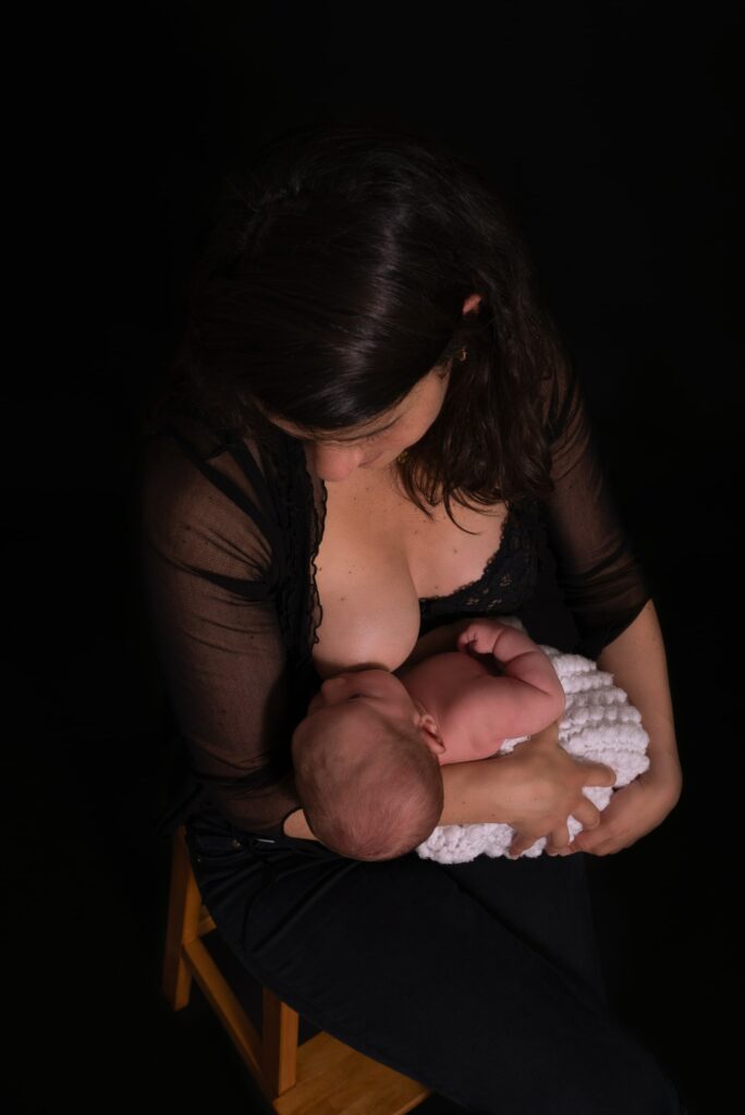 Fotografía de bebé tomando pecho con fondo oscuro Valencia