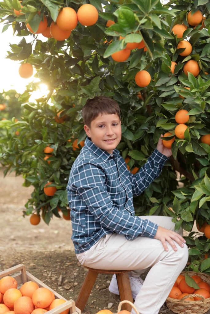 Niño explorando los naranjos al atardecer en Valencia